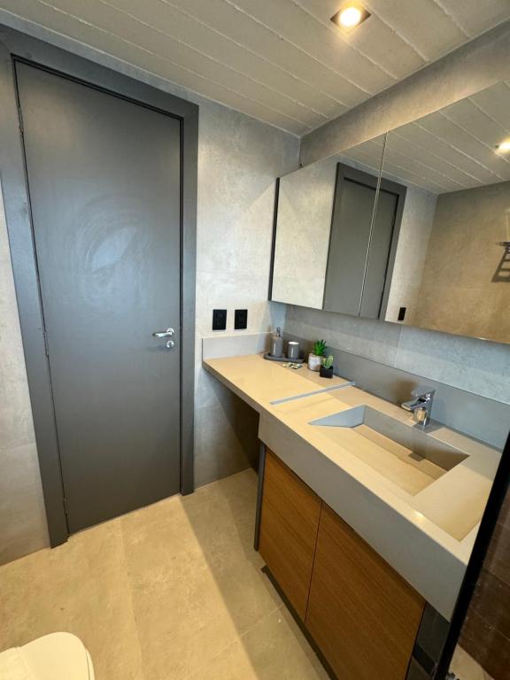 a bathroom with a sink and a large door at Luxuoso Studio particular reformado no Grand Mercure in Brasilia