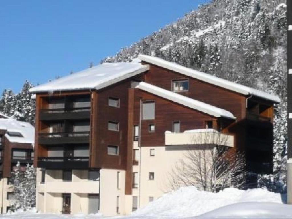 un edificio con nieve en el techo frente a una montaña en Résidence La Grande Traversee - Studio pour 4 Personnes 984 en Corrençon-en-Vercors