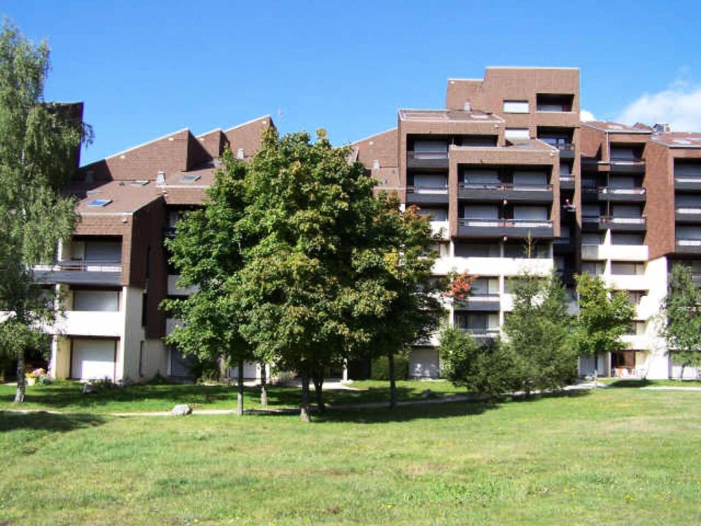 un gran edificio de apartamentos con un árbol delante en Résidence Tiolache - Studio pour 4 Personnes 094 en Corrençon-en-Vercors
