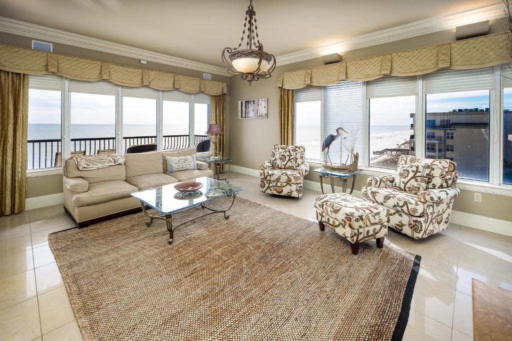 a living room with a couch and chairs and windows at South Beach 501: PENTHOUSE CONDO - UNPARALLELED QUALITY & LUXURY THROUGHOUT - in Fort Walton Beach