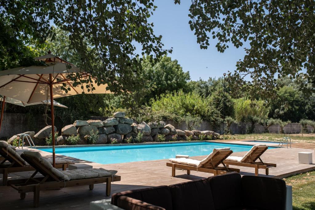a swimming pool with lounge chairs and an umbrella at Quinta do Louredo - Évora in Évora