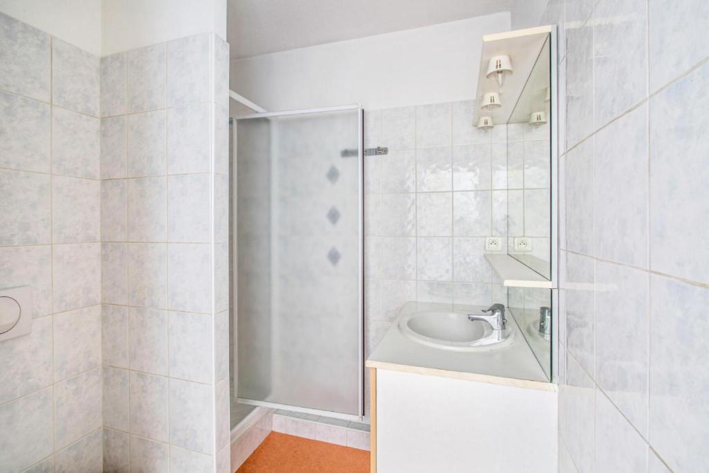 ein weißes Bad mit einer Dusche und einem Waschbecken in der Unterkunft Résidence Debussy - maeva Home - Appartement 2 Pièces 4 Personnes - Select 39 in Carnoux