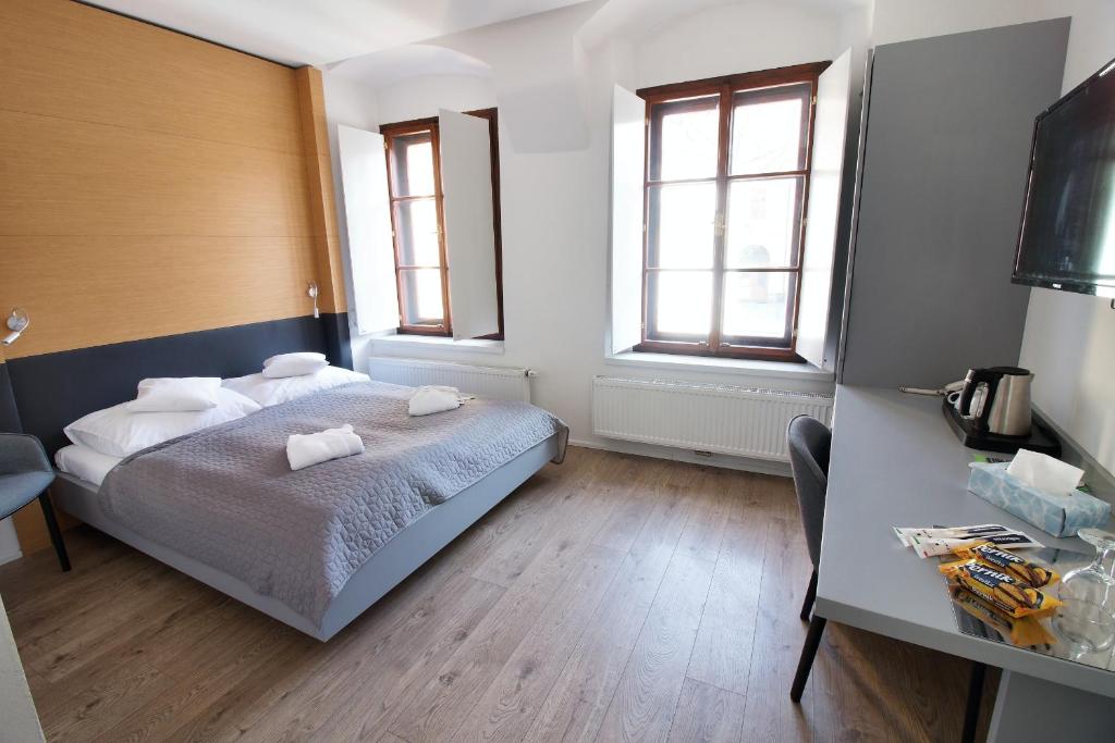 a bedroom with a bed and a desk and two windows at Hotel 100 in Pardubice