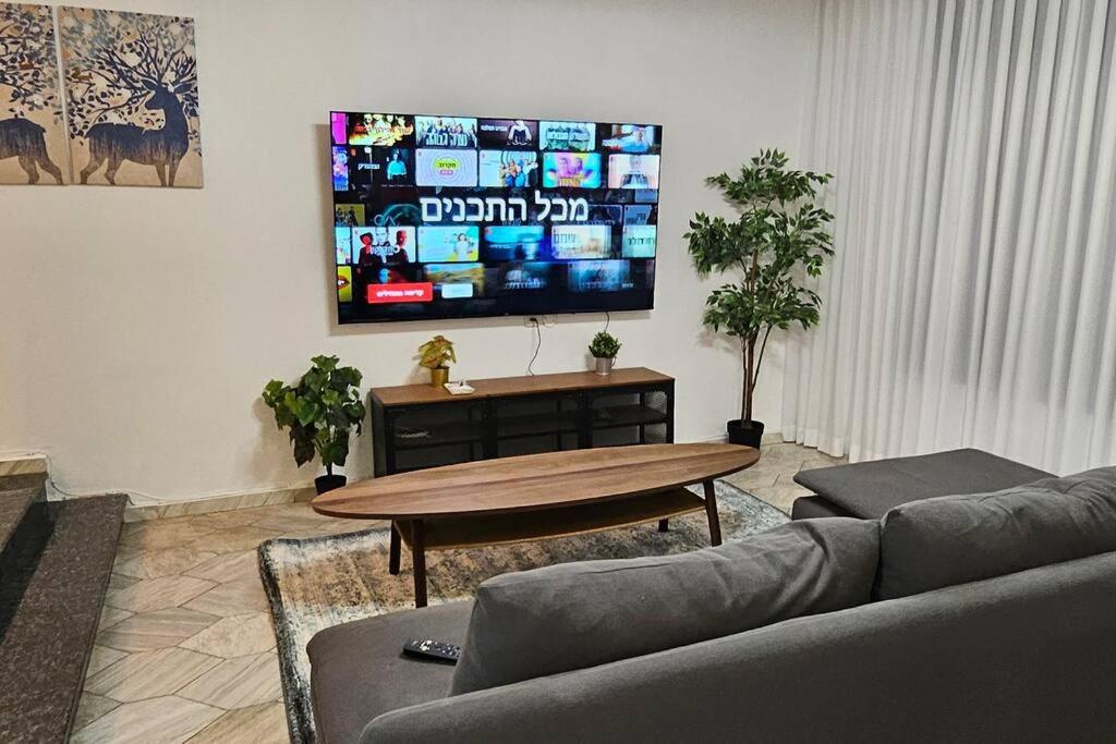 uma sala de estar com um sofá, uma mesa e uma televisão em גדולה ומעוצבת ברעננה em Ra‘ananna