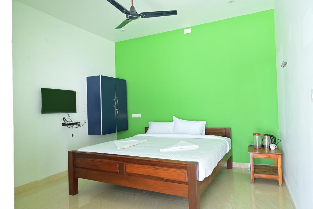 1 dormitorio con 1 cama con pared verde en Sea View JC Villa, en Kottakupam