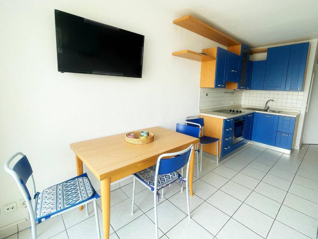 une cuisine avec une table en bois et des armoires bleues dans l'établissement Acquamarina Duplex dernier étage, à Villeneuve-Loubet
