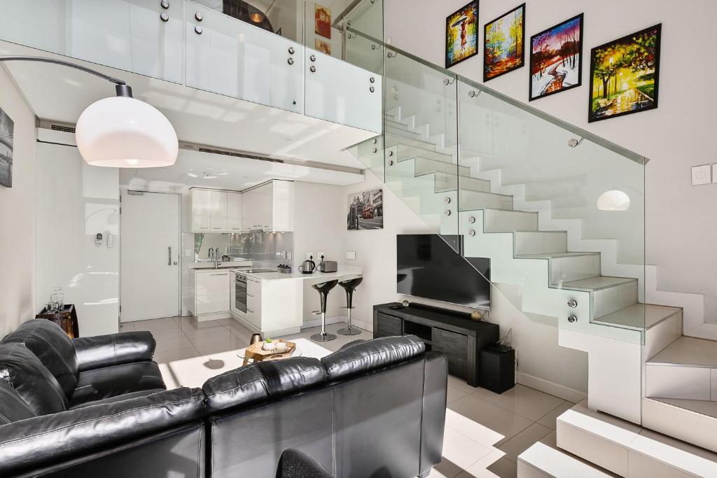 a living room with a couch and a staircase at Park Central Loft Apartment in Rosebank in Johannesburg