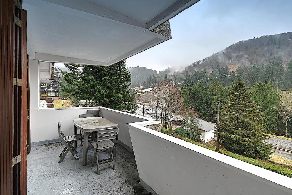 balcón con mesa y vistas a la montaña en Les Oursons - Station de ski accessible à pied, en La Bresse