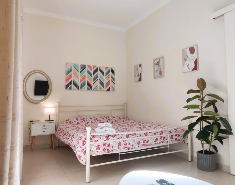 a white bedroom with a bed and a potted plant at Next to Metro! Bright Apartment with Fully Equipped Kitchen in Athens