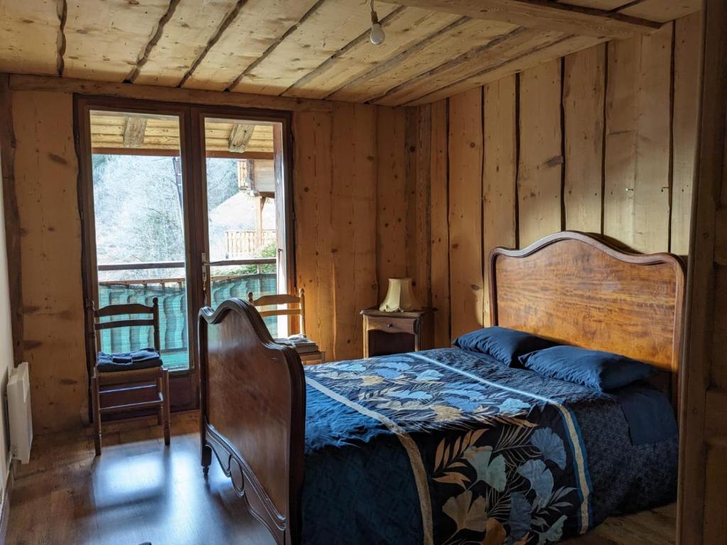 a bedroom with a bed in a room with wooden walls at Savoie, Simple mais confortable in Villard-sur-Doron
