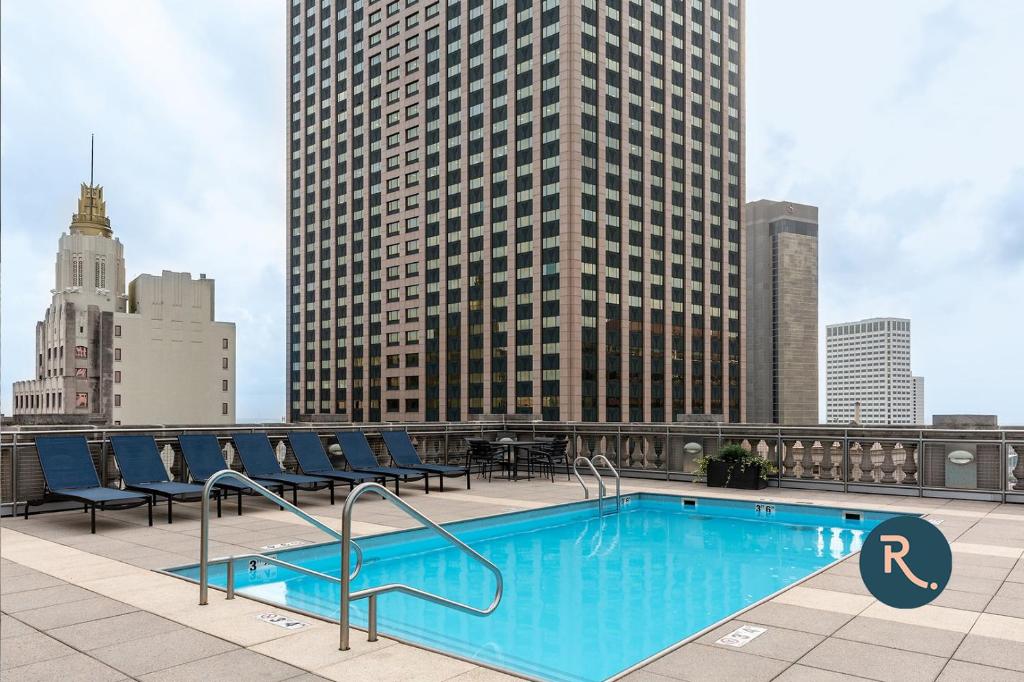 a swimming pool on the roof of a building with tall buildings at Roami at Hibernia Tower in New Orleans