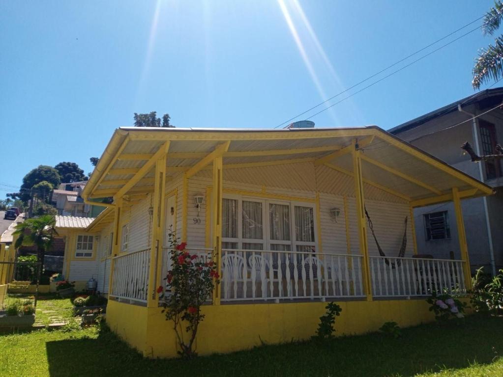 uma casa amarela com um alpendre e uma varanda em Residencial Di Capri em Gramado