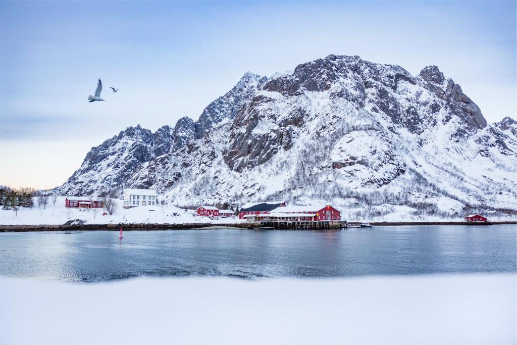 a snow covered mountain in front of a body of water at Kalle i Lofoten in Kabelvåg