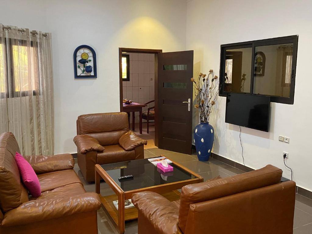 een woonkamer met lederen meubels en een televisie bij Cozy Apartment in Cotonou