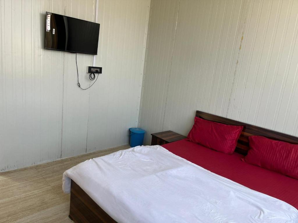 1 dormitorio con 1 cama con almohadas rojas y TV en Krishna fun land, en Mathura
