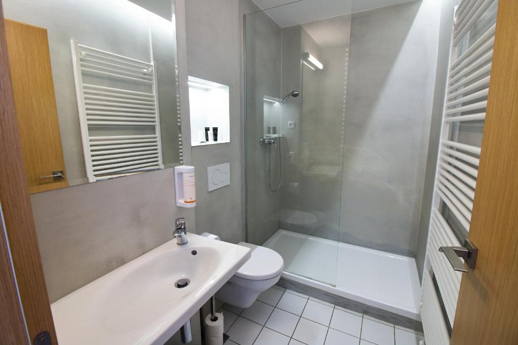 a bathroom with a sink and a toilet and a shower at Hotel 100 in Pardubice