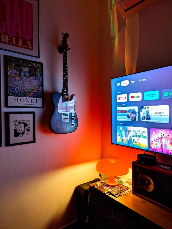 a guitar hanging on a wall next to a television at The Green Apartment - Central Malta - 2 Bedrooms, 2 Bathrooms in Msida