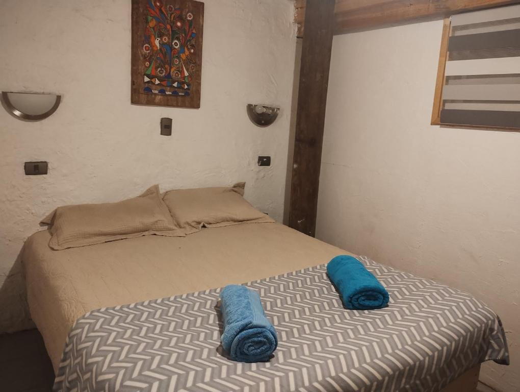 Una cama en una habitación con almohadas azules. en Cabañas del mar, en Maitencillo