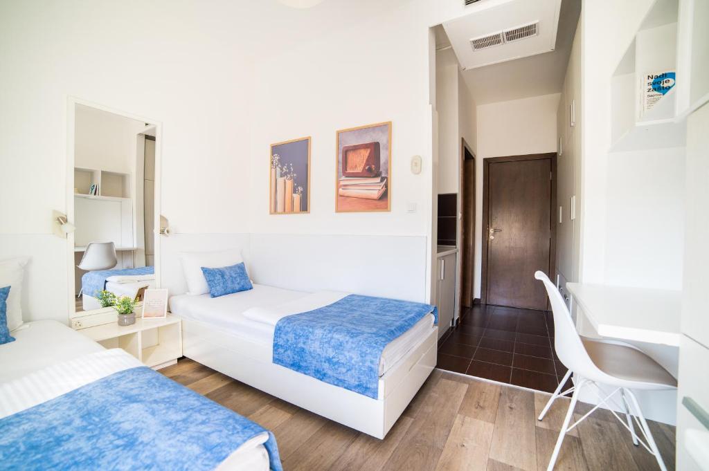 1 dormitorio con 2 camas y escritorio en University Hotel Dorrah, en Tuzla