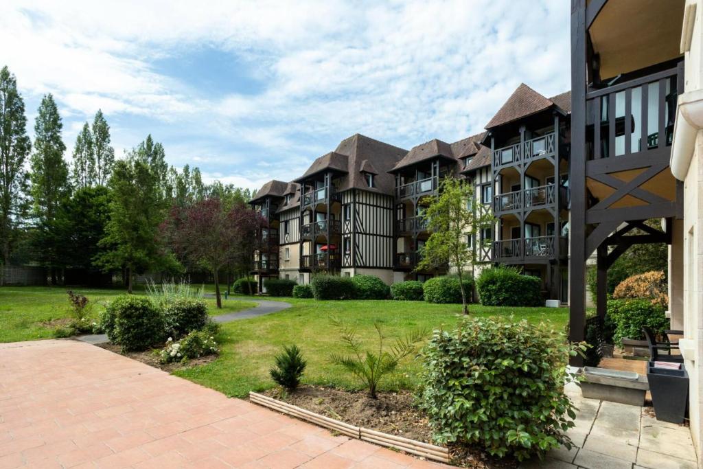un gran edificio de apartamentos con un patio de césped en La Résidence du Golf - maeva Home - Appartement 2 pièces 4 personnes - Conf 38, en Deauville