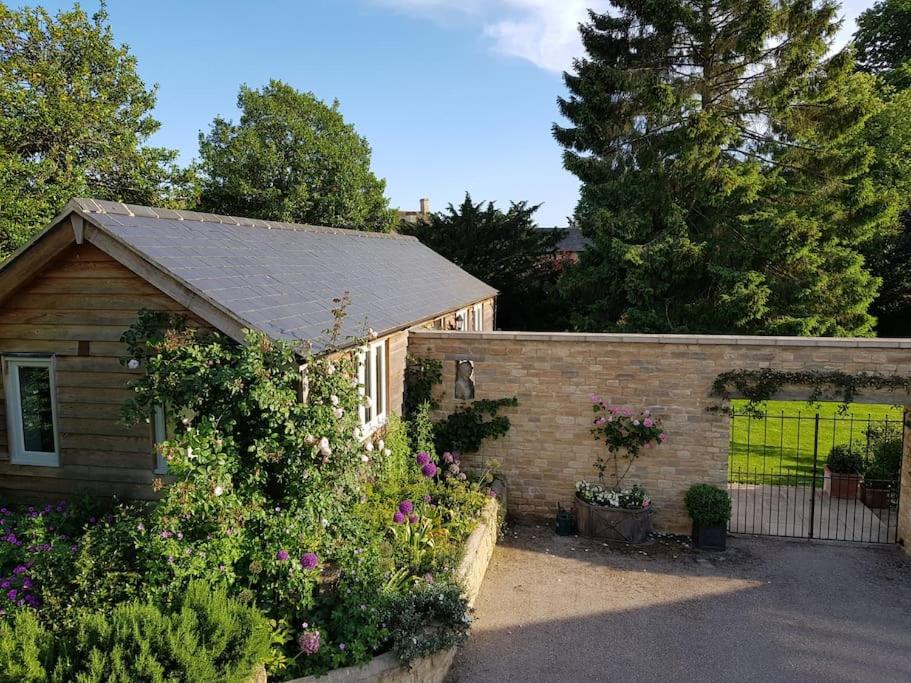 uma casa com um jardim com flores e uma cerca em Charming Cottage surrounded by Idyllic garden in peaceful location in central Charlbury em Charlbury