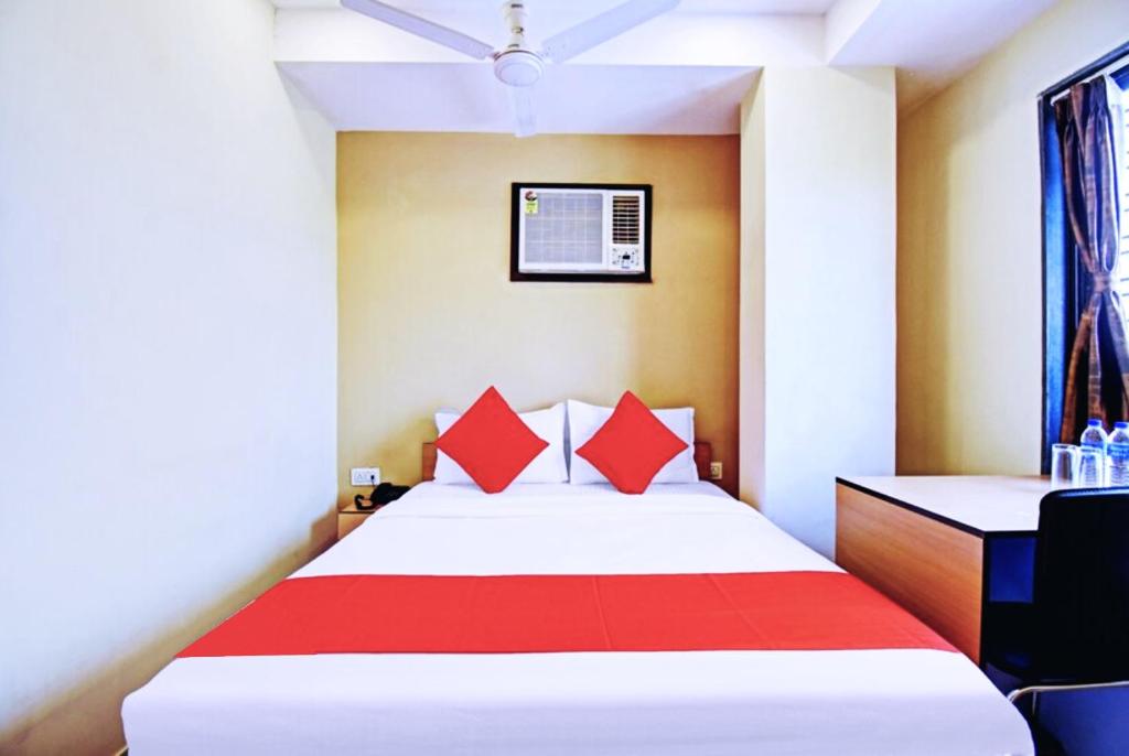 a bedroom with a bed with red pillows at Hotel Elite Inn Ultadanga Inn Kolkata in Kolkata