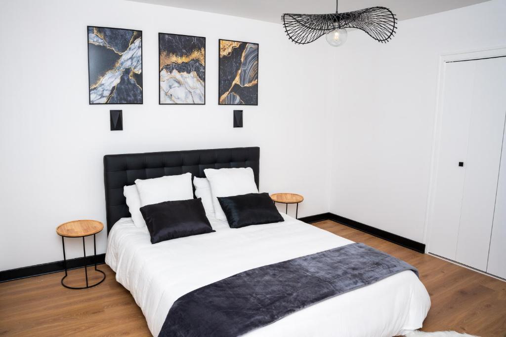 a bedroom with a black and white bed and pictures on the wall at L'Orée des Champs 