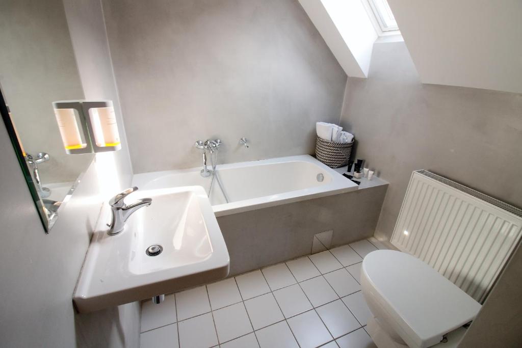 a bathroom with a sink and a tub and a toilet at Hotel 100 in Pardubice