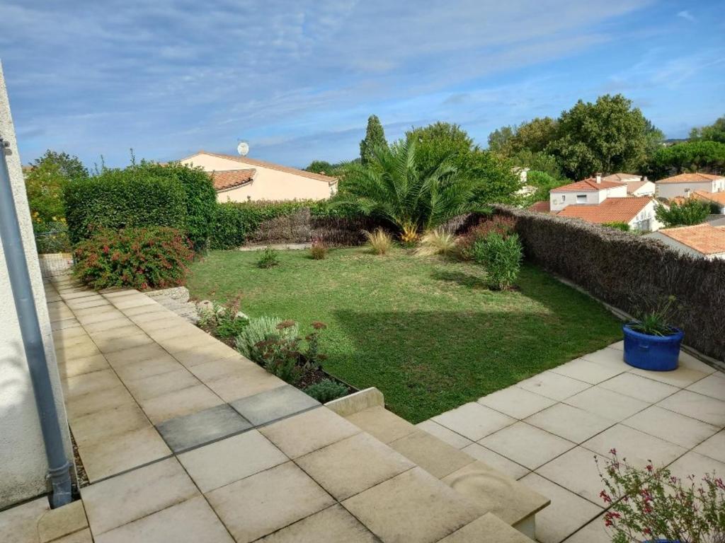une arrière-cour avec une pelouse et un jardin dans l'établissement Maison 3 ch. à Royan avec jardin, WIFI et animaux acceptés - FR-1-494-143, à Royan