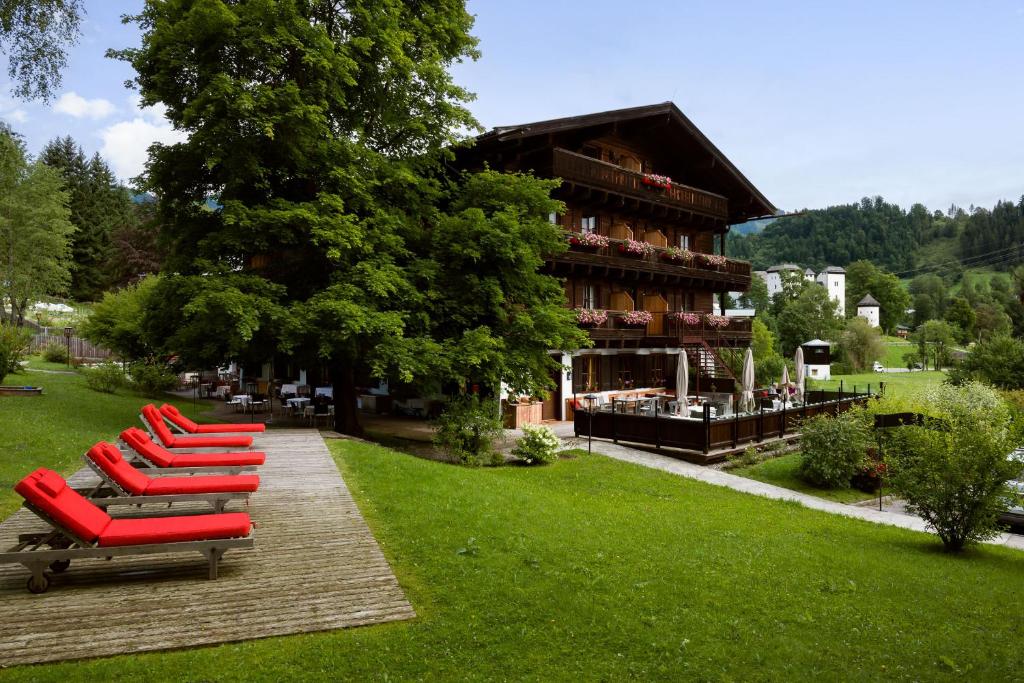 een rij rode ligstoelen voor een gebouw bij Hotel zur Post in Goldegg