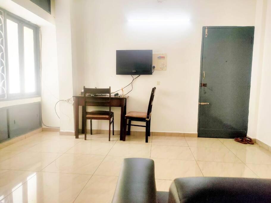 a living room with a table and a desk with a television at Good stay service apartments cenotaph road in Chennai