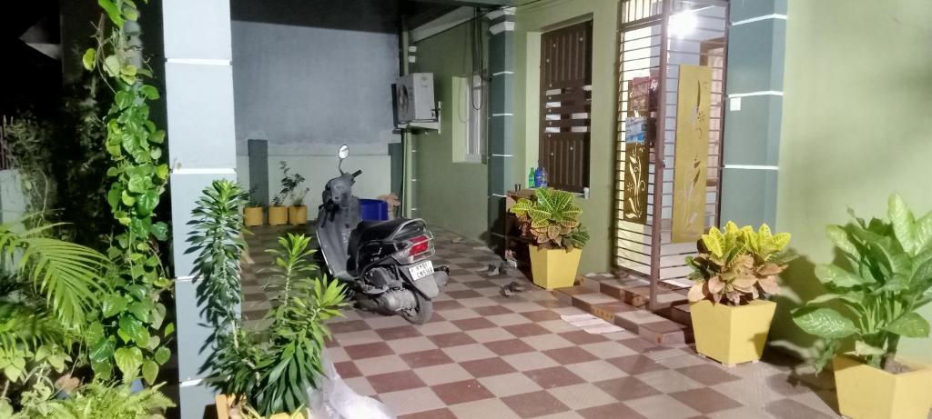 a motorcycle parked in a room with plants at AVAR Home syay in Virāmpattinam