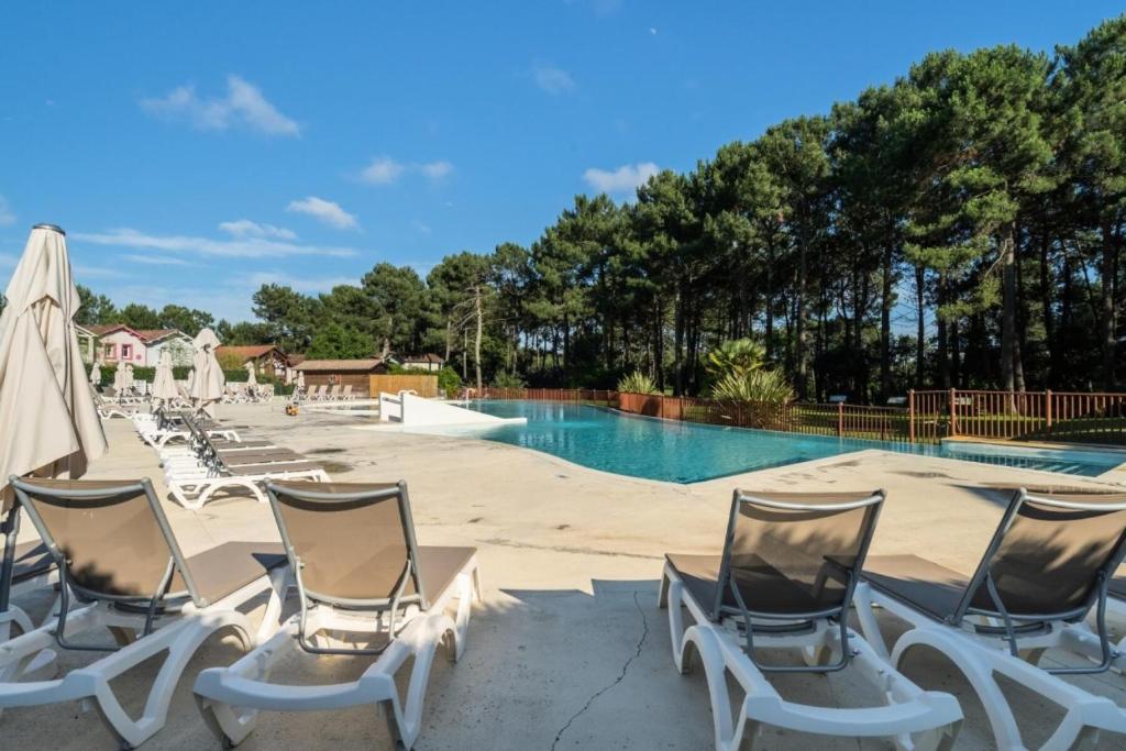 a group of lawn chairs sitting next to a swimming pool at Résidence Lacanau Les Pins - maeva Home - Appartement 2 Pièces 5 Personnes 27 in Lacanau