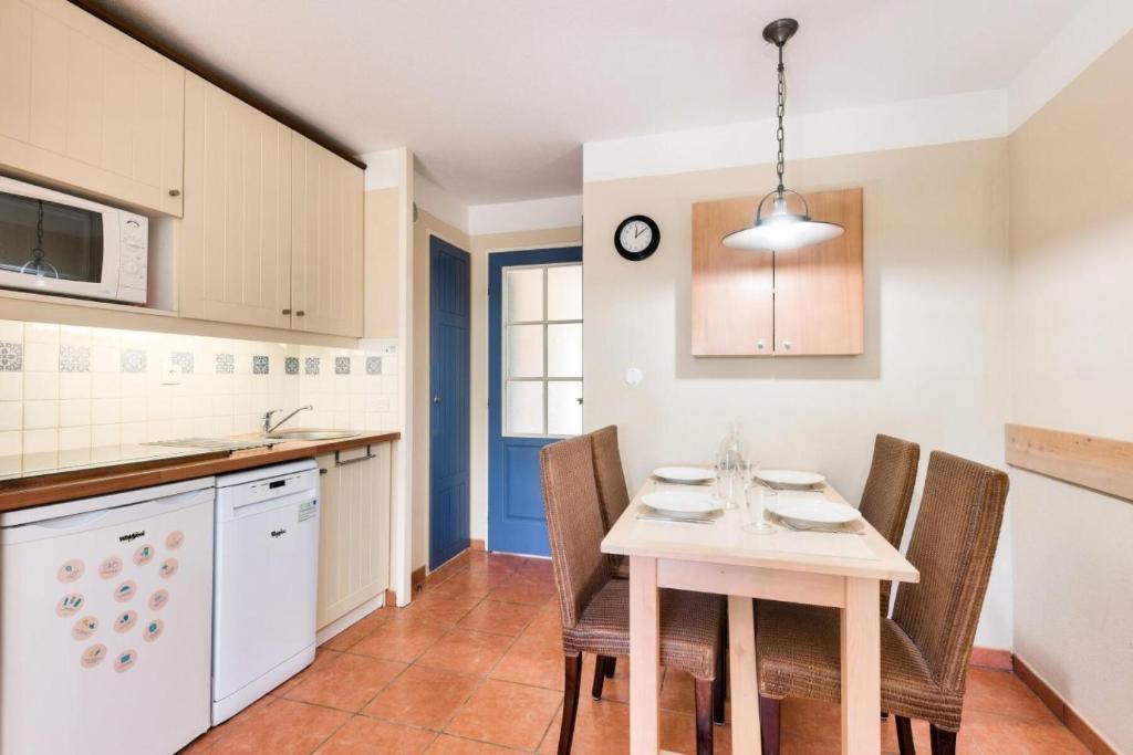 a kitchen with a table and chairs in it at Résidence Lacanau Les Pins - maeva Home - Appartement 2 Pièces 5 Personnes 27 in Lacanau