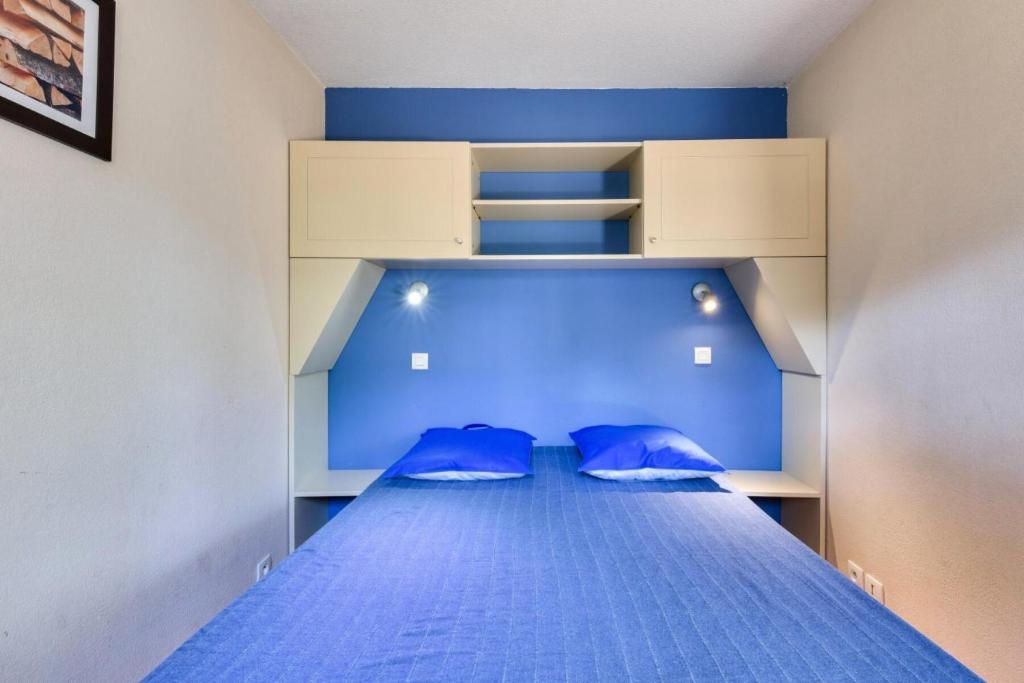 a bedroom with a blue bed with blue pillows at Résidence Lacanau Les Pins - maeva Home - Appartement 2 Pièces 5 Personnes 27 in Lacanau