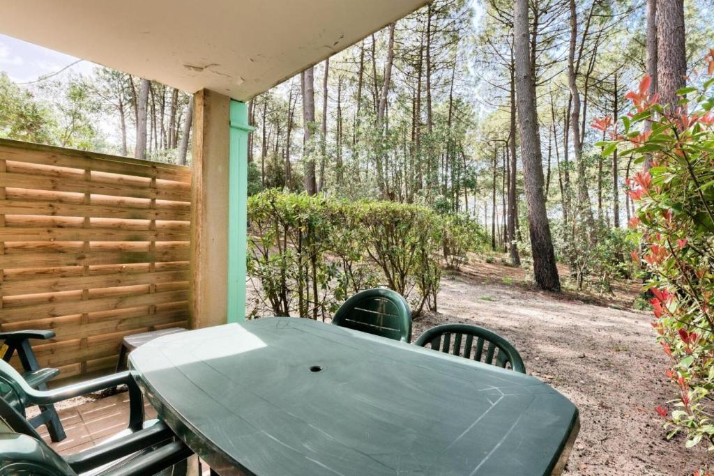 a table and chairs on the back porch of a cabin at Résidence Lacanau Les Pins - maeva Home - Appartement 2 Pièces 5 Personnes 27 in Lacanau