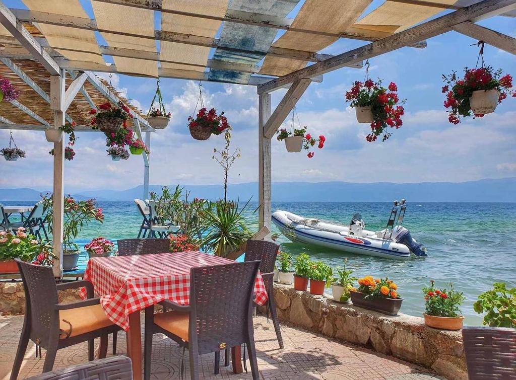 a table and chairs with a boat in the water at Villa Radozda in Struga