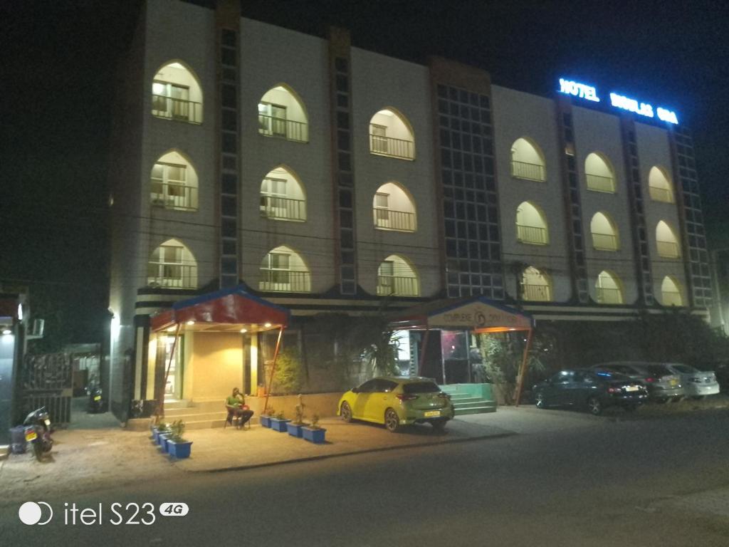 a building with a yellow car parked in front of it at Hôtel Dioulassoba in Bobo-Dioulasso