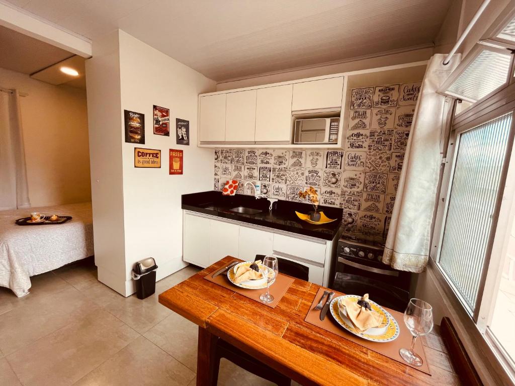 a small kitchen with a wooden table and a dining room at Loft encantador A - 8 km de Floripa in São José