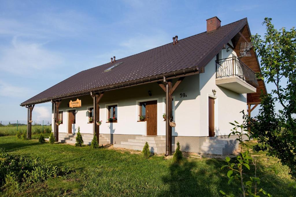 een wit huis met een zwart dak bij Agroturystyka Golubie in Ełk