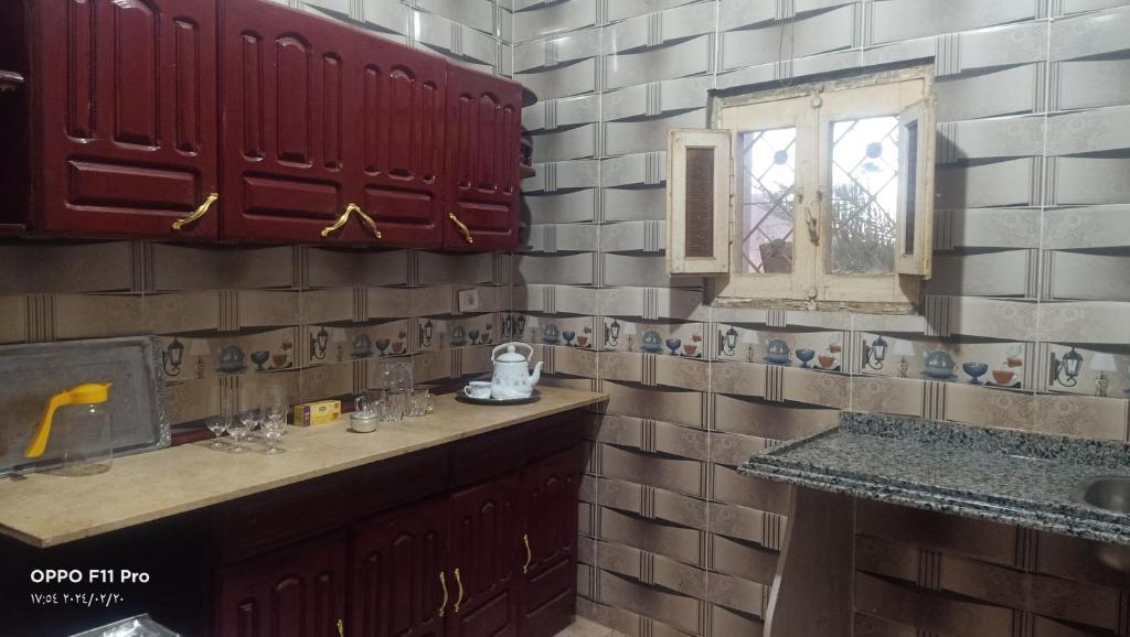 a kitchen with red and white tiled walls and a window at Amon guest house in Abu Simbel