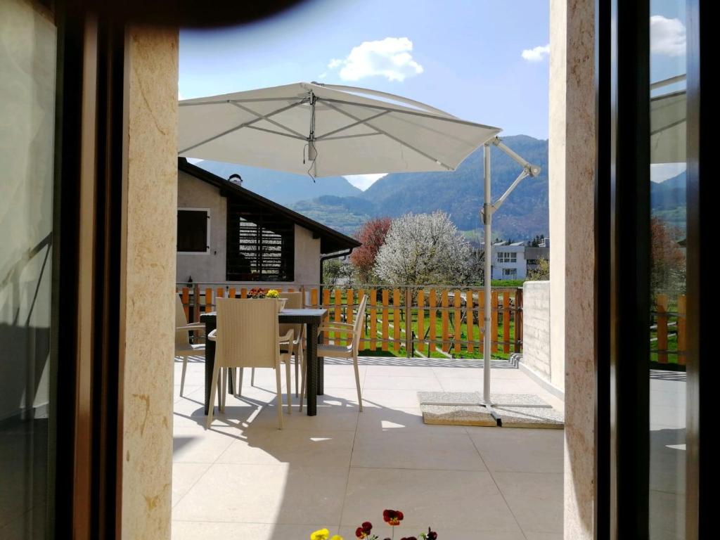 un patio con una mesa y una sombrilla en Suite alla Terrazza, en Comano Terme