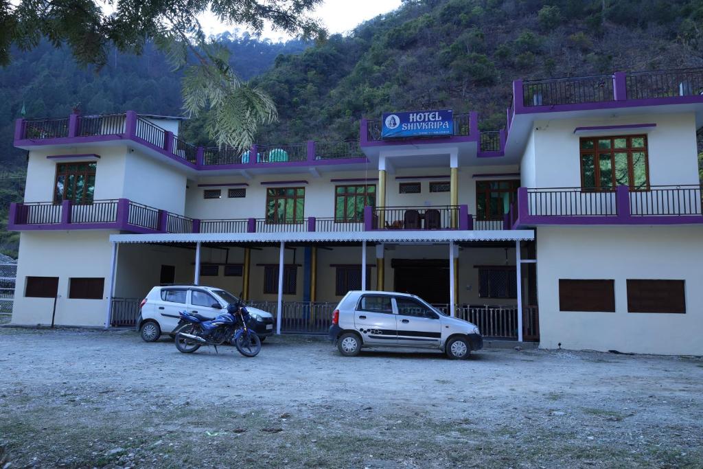 een gebouw met twee auto's ervoor geparkeerd bij HOTEL SHIVKRIPA AND RESTAURANT in Dharāsu