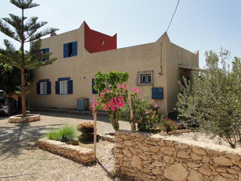 a house with a stone wall and flowers in front of it at Dar Fati Roses in Aït Imouni