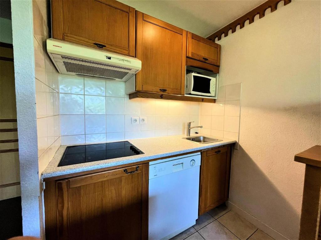 a small kitchen with wooden cabinets and a sink at Résidence Bosson - 2 Pièces pour 6 Personnes 844 in Les Menuires