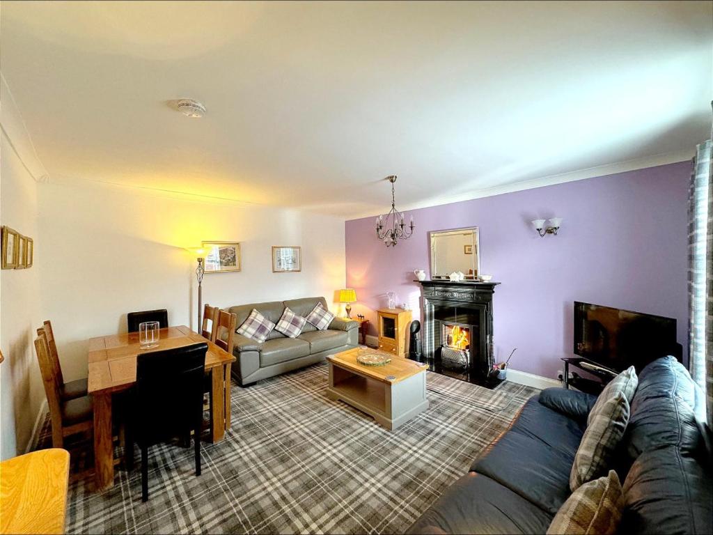 a living room with a couch and a fireplace at Ameliafield Cottage, Prestwick in Prestwick
