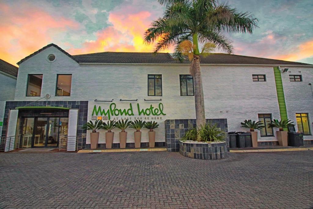 a building with a palm tree in front of it at MyPond Stenden Hotel in Port Alfred