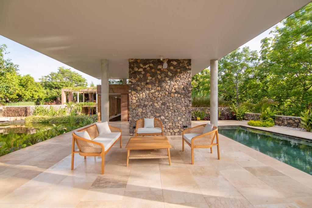 een patio met 2 stoelen, een tafel en een zwembad bij Villa Lantana in Umeanyar