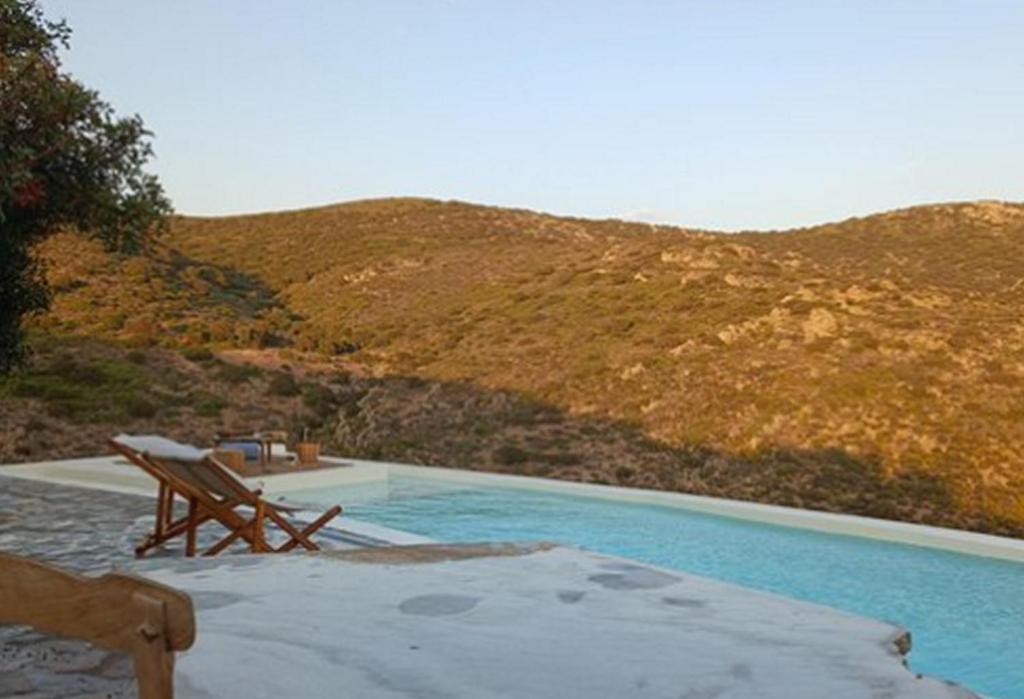 Stunning Antiparos Villa 3 Bedrooms Villa Kamino Breathtaking Sea Views في أنديباروس: حمام سباحة مع كرسي بجوار جبل