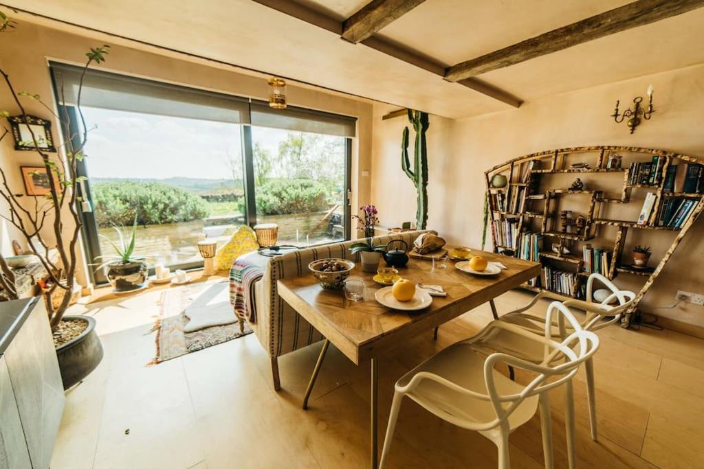 uma sala de estar com uma mesa e uma grande janela em Romantic Country Annex With Views - 10 min to Bath em Cold Ashton